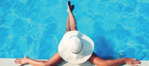 Guest relaxing at the edge of a bright blue pool